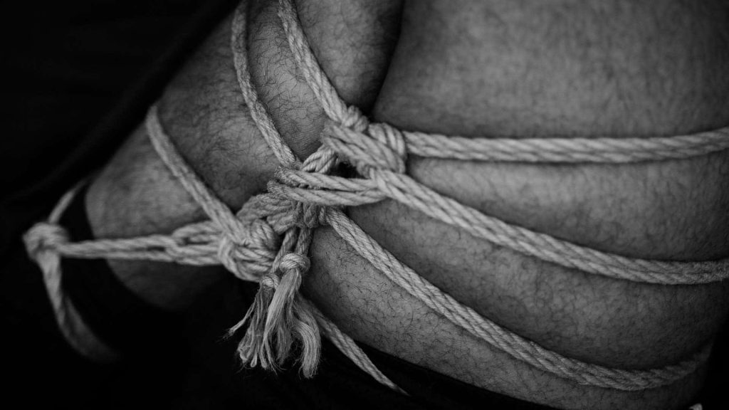 A man's legs tied together with rope