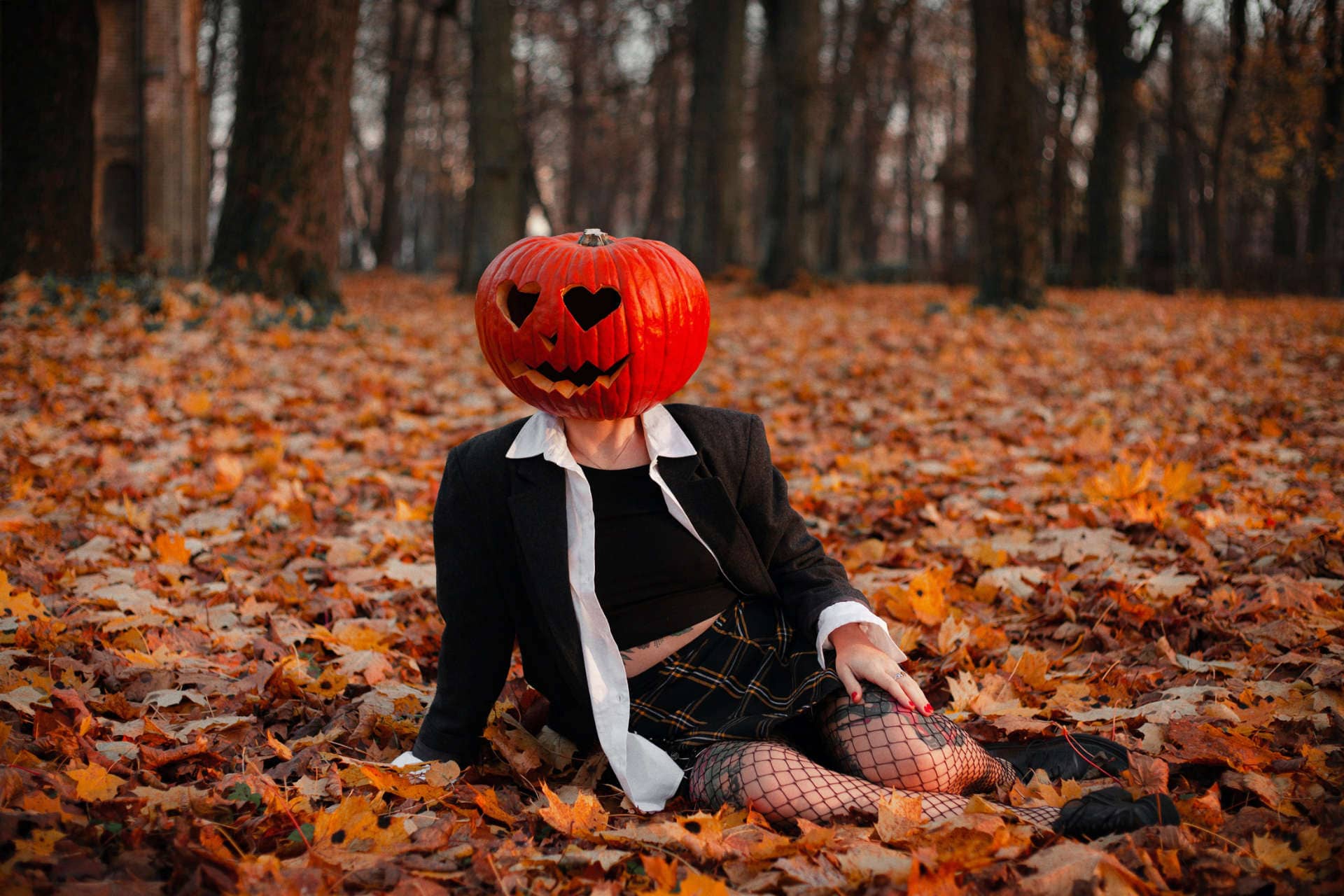 Woman wearing pumpkin sitting on leafs