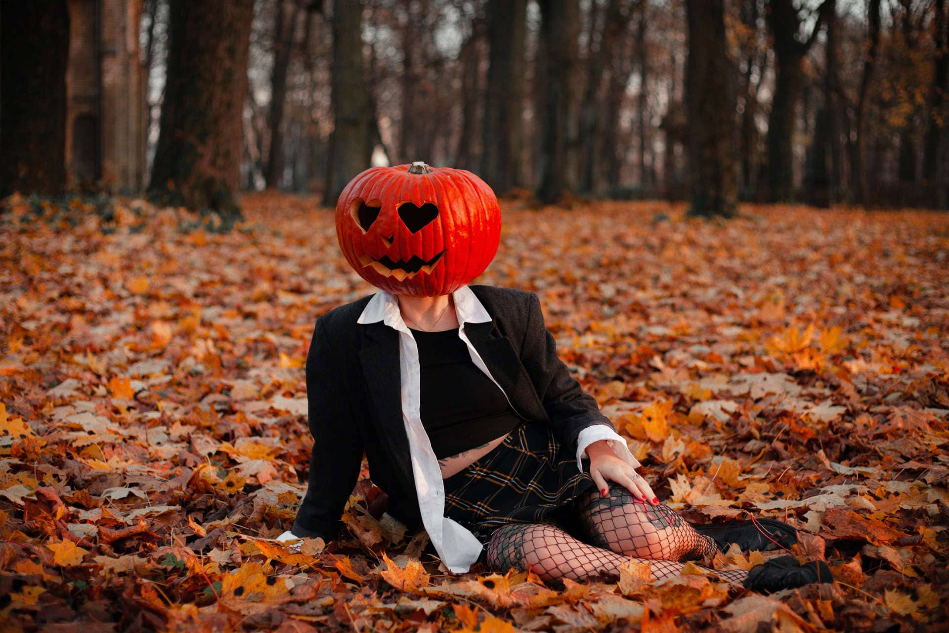 Woman wearing pumpkin sitting on leafs