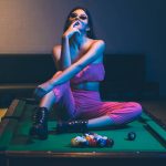 Young woman sitting on pool table
