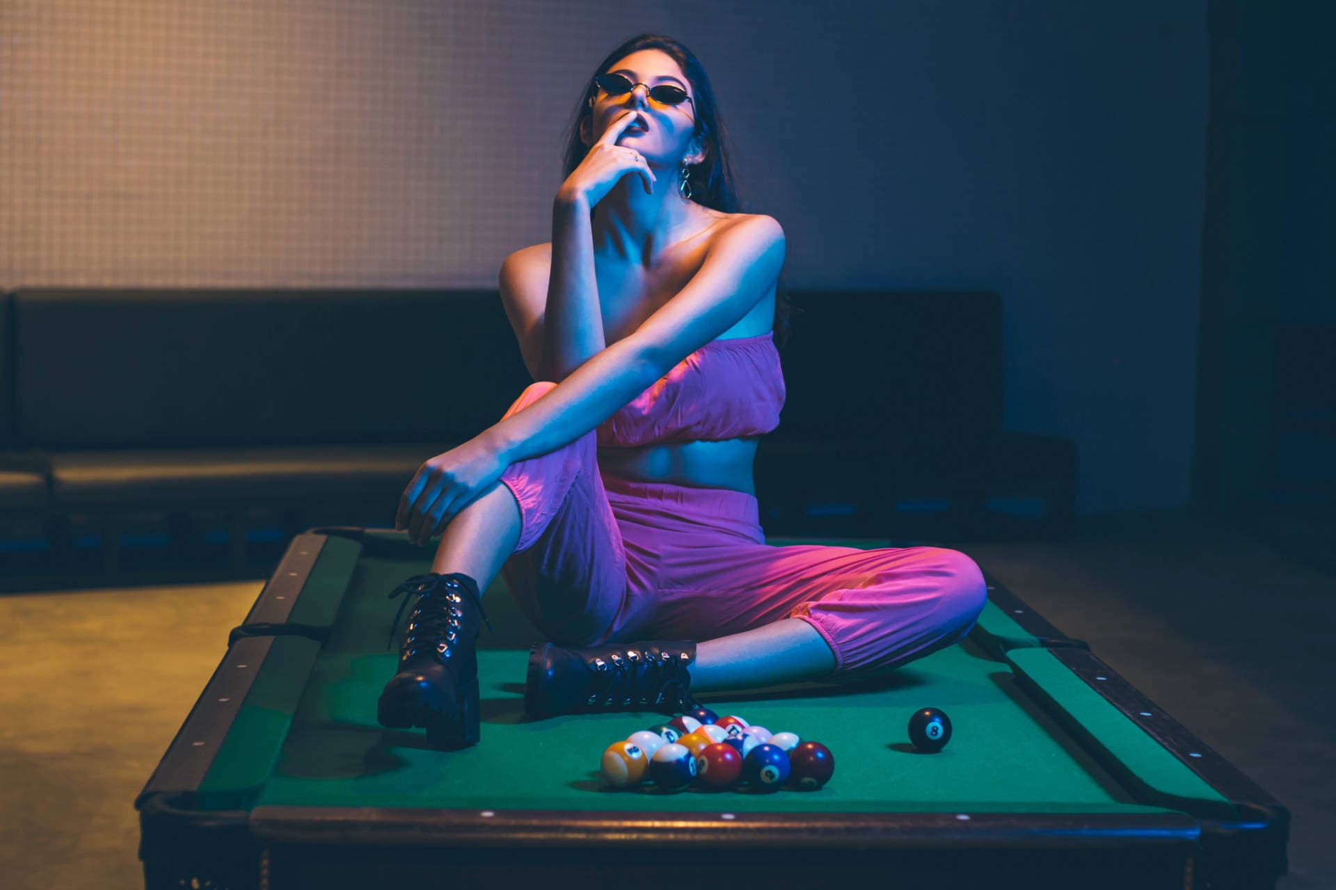 Young woman sitting on pool table